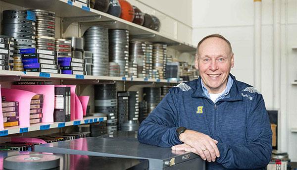 Terry Gurnett posing in front of shelves of film reels